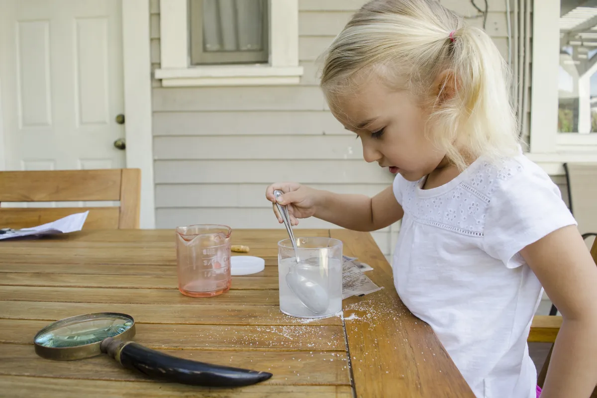 Niña pintando agua de colores en vasos